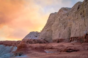 Cramer Imaging's fine art landscape photograph of orange smoke in the sky over the red and white cliffs of Escalante National Monument, Utah